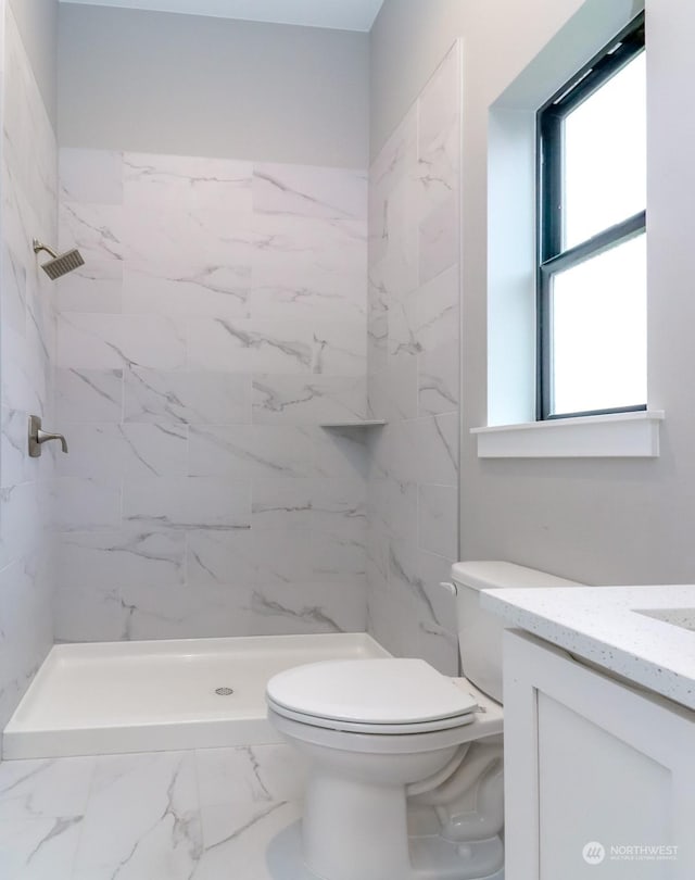 bathroom featuring toilet, a tile shower, and vanity