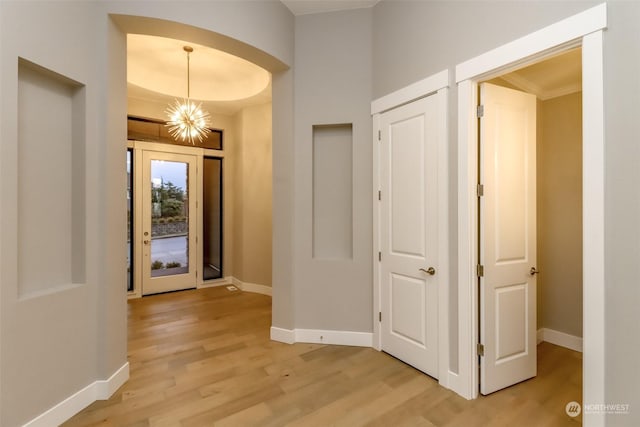 corridor featuring a chandelier, light hardwood / wood-style floors, and ornamental molding