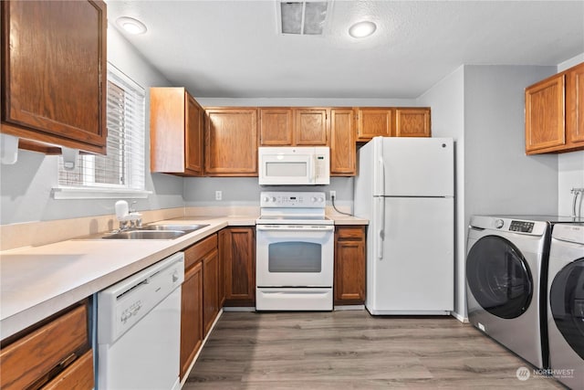 kitchen with sink, washing machine and dryer, hardwood / wood-style floors, a textured ceiling, and white appliances