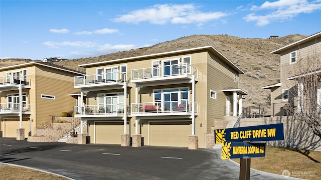 view of building exterior featuring stairs, aphalt driveway, an attached garage, and a mountain view