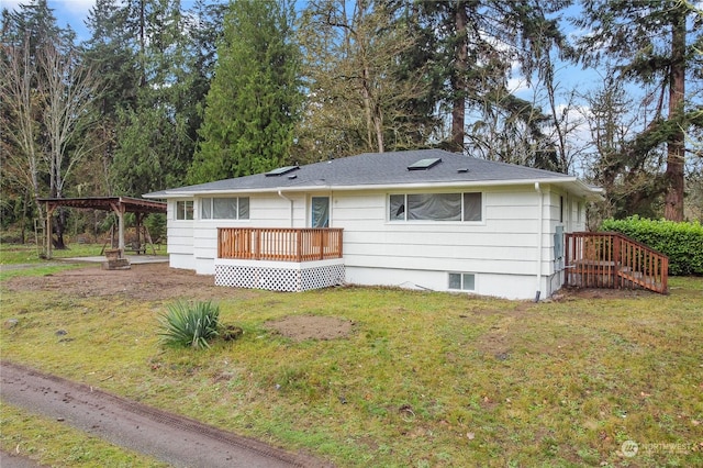 rear view of house with a wooden deck and a lawn