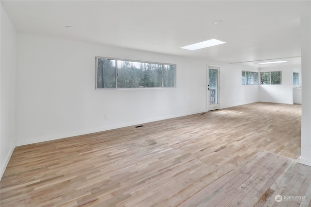 spare room featuring light wood-type flooring and plenty of natural light