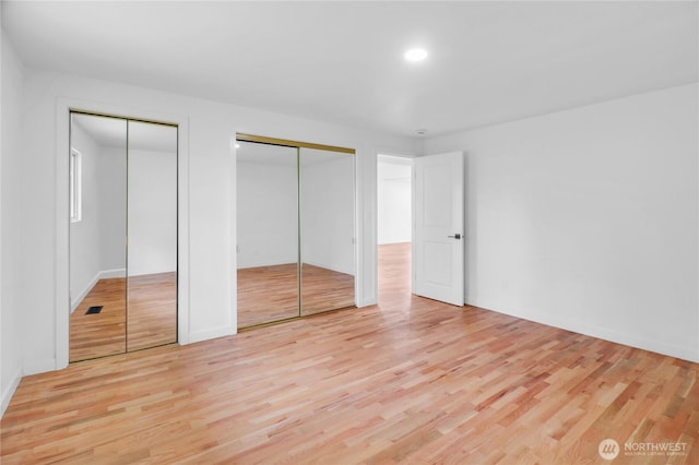 unfurnished bedroom with multiple closets, light wood-style floors, baseboards, and recessed lighting