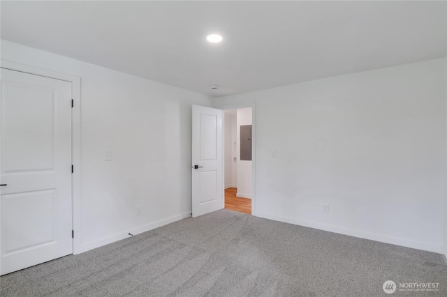 carpeted empty room featuring baseboards and electric panel