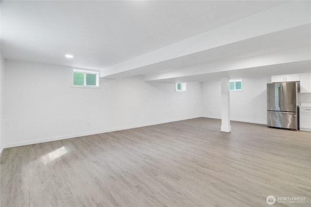 basement with freestanding refrigerator, light wood-style flooring, baseboards, and recessed lighting