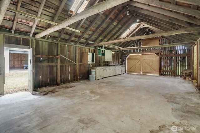 miscellaneous room with lofted ceiling, unfinished concrete floors, and electric panel