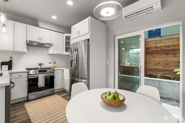 kitchen with appliances with stainless steel finishes, pendant lighting, white cabinetry, and a wall unit AC