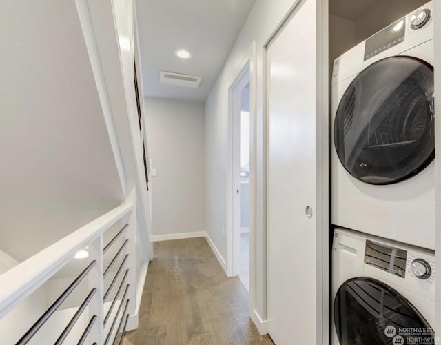 washroom featuring stacked washer and dryer and light wood-type flooring