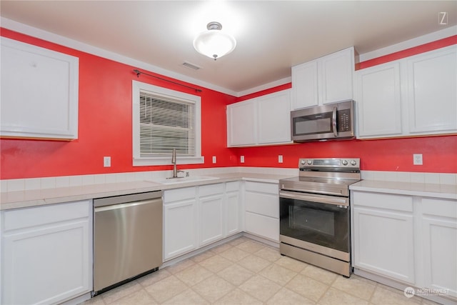 kitchen with appliances with stainless steel finishes, white cabinetry, and sink