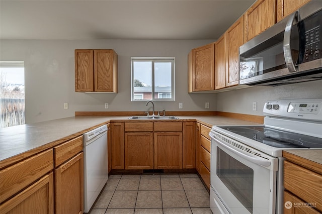 kitchen featuring kitchen peninsula, light tile patterned floors, white appliances, and sink