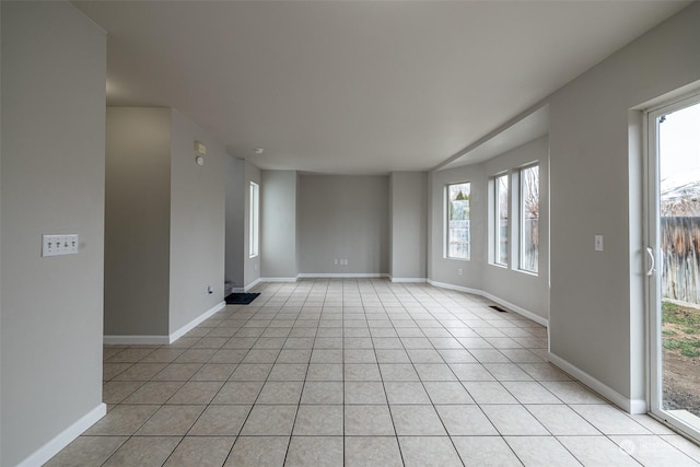 empty room with a healthy amount of sunlight and light tile patterned flooring