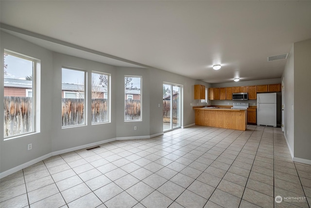 kitchen with range, kitchen peninsula, light tile patterned flooring, and white refrigerator