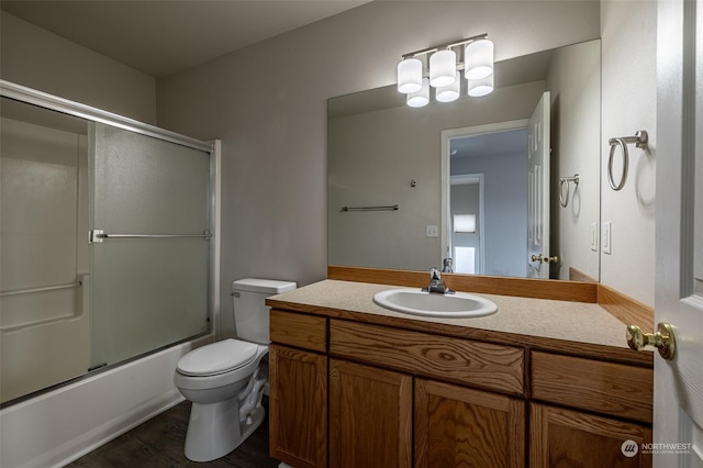 full bathroom featuring toilet, vanity, wood-type flooring, and combined bath / shower with glass door