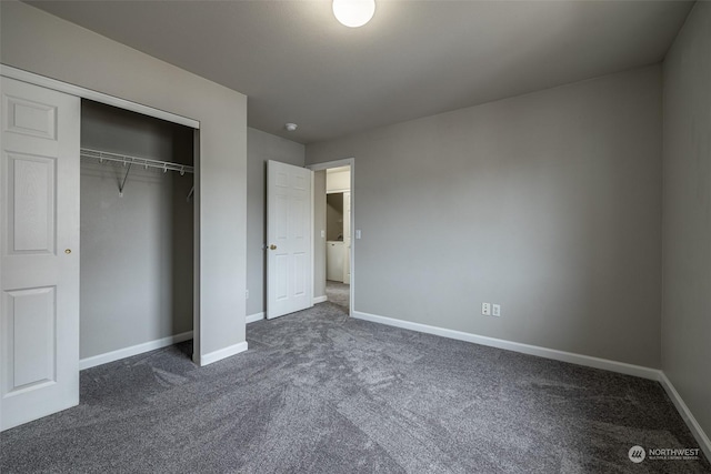 unfurnished bedroom featuring dark carpet, washer / dryer, and a closet