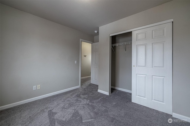 unfurnished bedroom with dark colored carpet and a closet