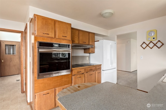 kitchen featuring black electric cooktop, oven, and white fridge