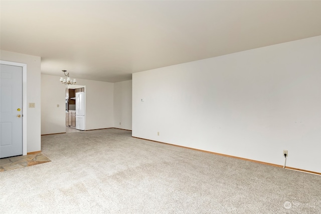 carpeted empty room featuring a chandelier