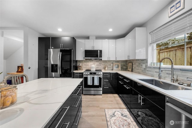 kitchen with backsplash, stainless steel appliances, sink, light hardwood / wood-style flooring, and white cabinetry