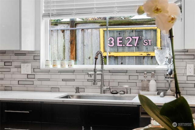 kitchen with decorative backsplash, sink, white cabinets, and light stone countertops