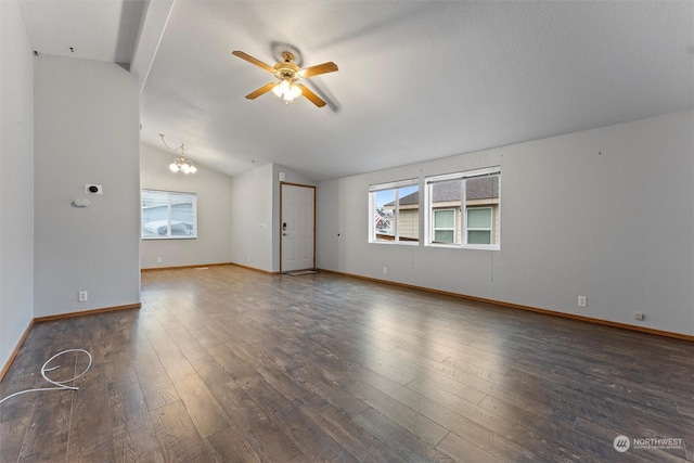 spare room featuring ceiling fan with notable chandelier, dark hardwood / wood-style flooring, and vaulted ceiling