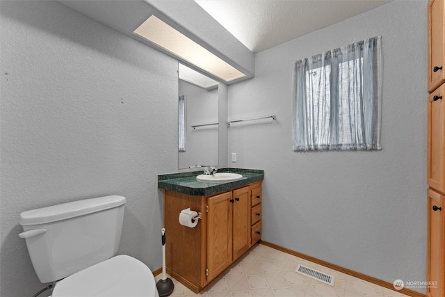 bathroom featuring vanity, toilet, and a textured ceiling