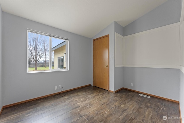 unfurnished bedroom featuring a closet, dark hardwood / wood-style flooring, and vaulted ceiling