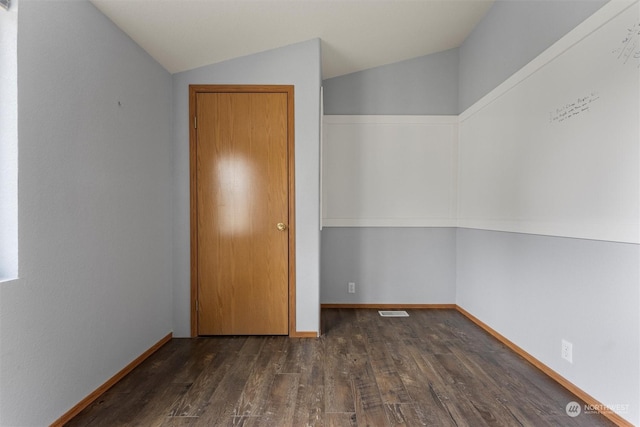 empty room featuring dark hardwood / wood-style flooring and lofted ceiling