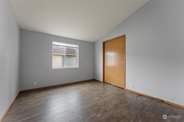 empty room with dark hardwood / wood-style flooring and vaulted ceiling