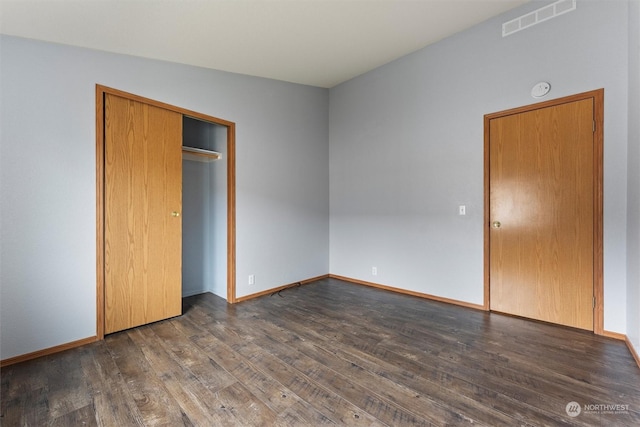 unfurnished bedroom with a closet, dark wood-type flooring, and lofted ceiling