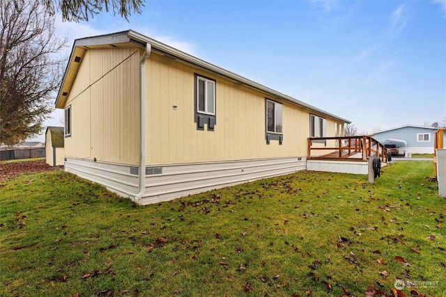 view of side of property featuring a lawn and a wooden deck