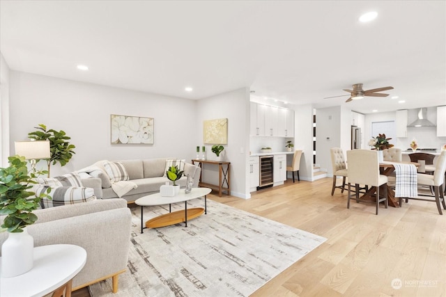 living room with wine cooler, ceiling fan, and light hardwood / wood-style flooring