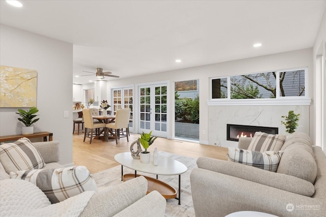 living room featuring a fireplace, light wood-type flooring, and ceiling fan