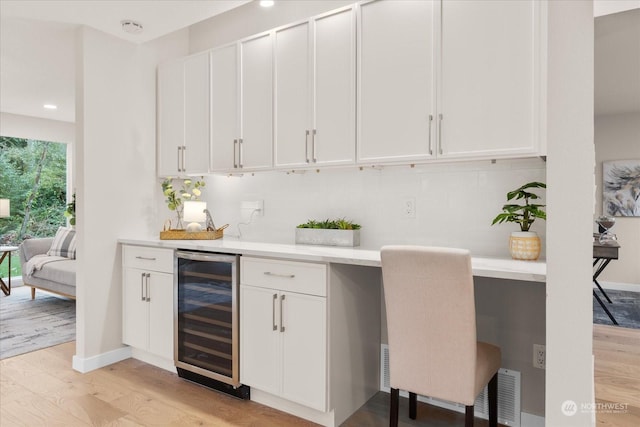 bar with white cabinets, light hardwood / wood-style floors, and beverage cooler