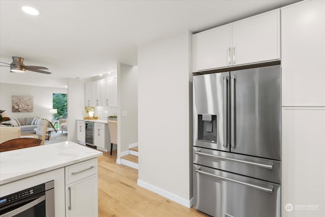 kitchen featuring wine cooler, white cabinetry, light hardwood / wood-style flooring, and stainless steel appliances