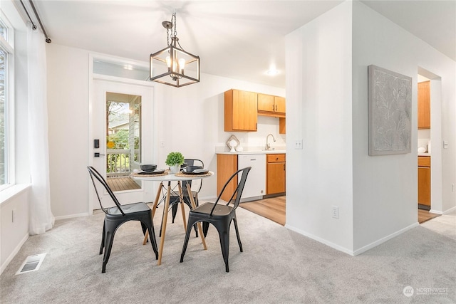 dining space with a chandelier, light colored carpet, and sink