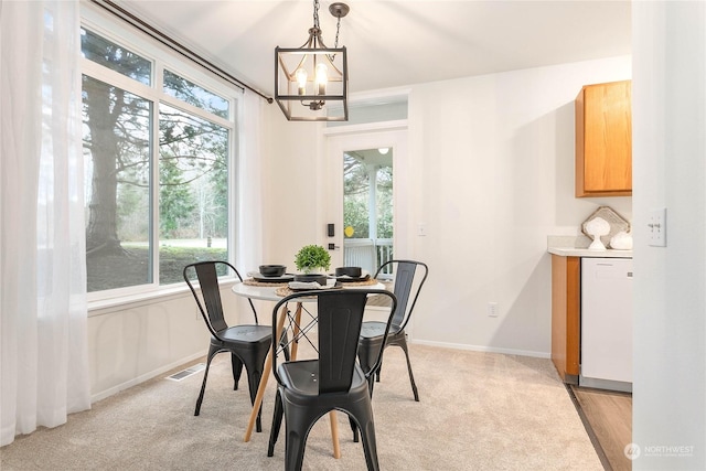 carpeted dining area with a healthy amount of sunlight and a chandelier