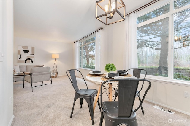 carpeted dining area featuring an inviting chandelier and a healthy amount of sunlight