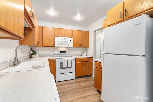 kitchen with light hardwood / wood-style floors, white appliances, and sink