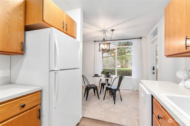 kitchen featuring sink, a notable chandelier, white appliances, decorative light fixtures, and light wood-type flooring