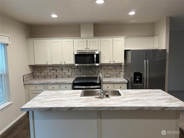 kitchen featuring appliances with stainless steel finishes, a kitchen island with sink, dark wood-type flooring, sink, and white cabinetry