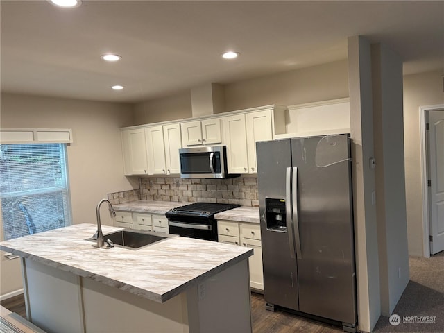 kitchen featuring tasteful backsplash, stainless steel appliances, a kitchen island with sink, sink, and white cabinets