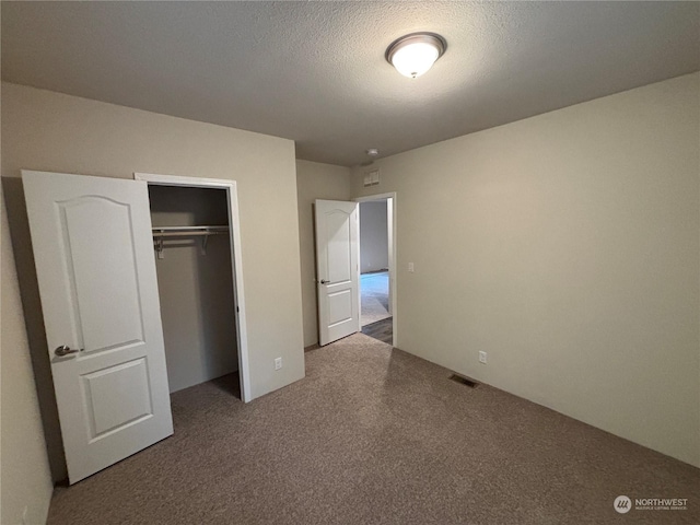 unfurnished bedroom featuring carpet, a textured ceiling, and a closet