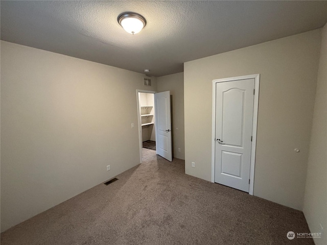 unfurnished bedroom featuring carpet, visible vents, and a textured ceiling