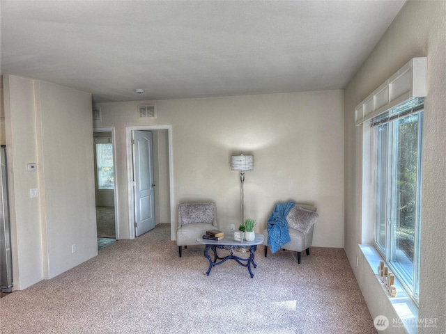 sitting room with carpet floors, plenty of natural light, and visible vents