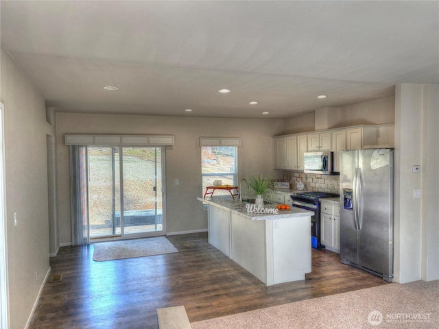 kitchen with dark wood-style flooring, a center island, stainless steel appliances, light countertops, and backsplash