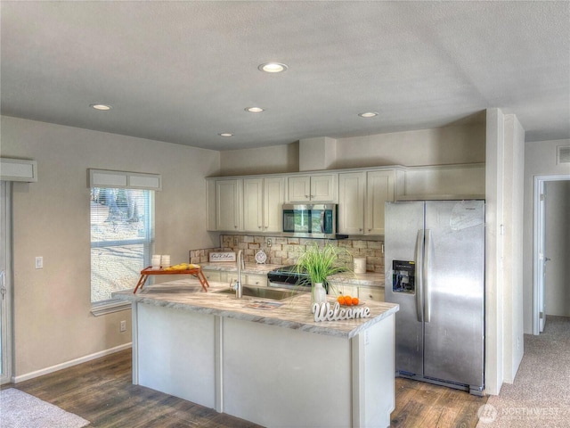 kitchen featuring baseboards, appliances with stainless steel finishes, dark wood-type flooring, a sink, and backsplash