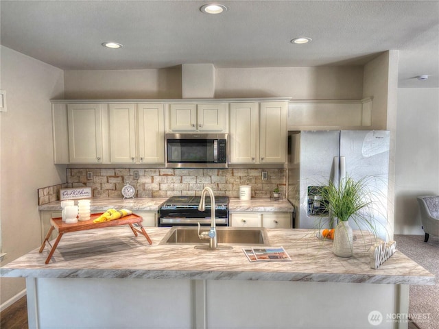 kitchen featuring recessed lighting, a sink, light countertops, appliances with stainless steel finishes, and backsplash