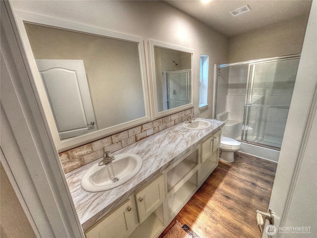 full bathroom featuring a stall shower, visible vents, a sink, and wood finished floors