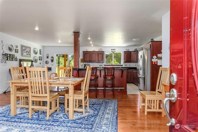 dining space featuring light wood-type flooring, a wealth of natural light, and ornate columns