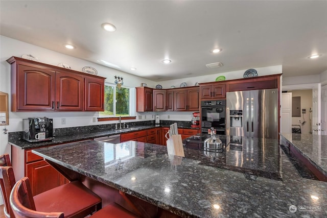 kitchen featuring dark stone counters, a breakfast bar, sink, and stainless steel appliances